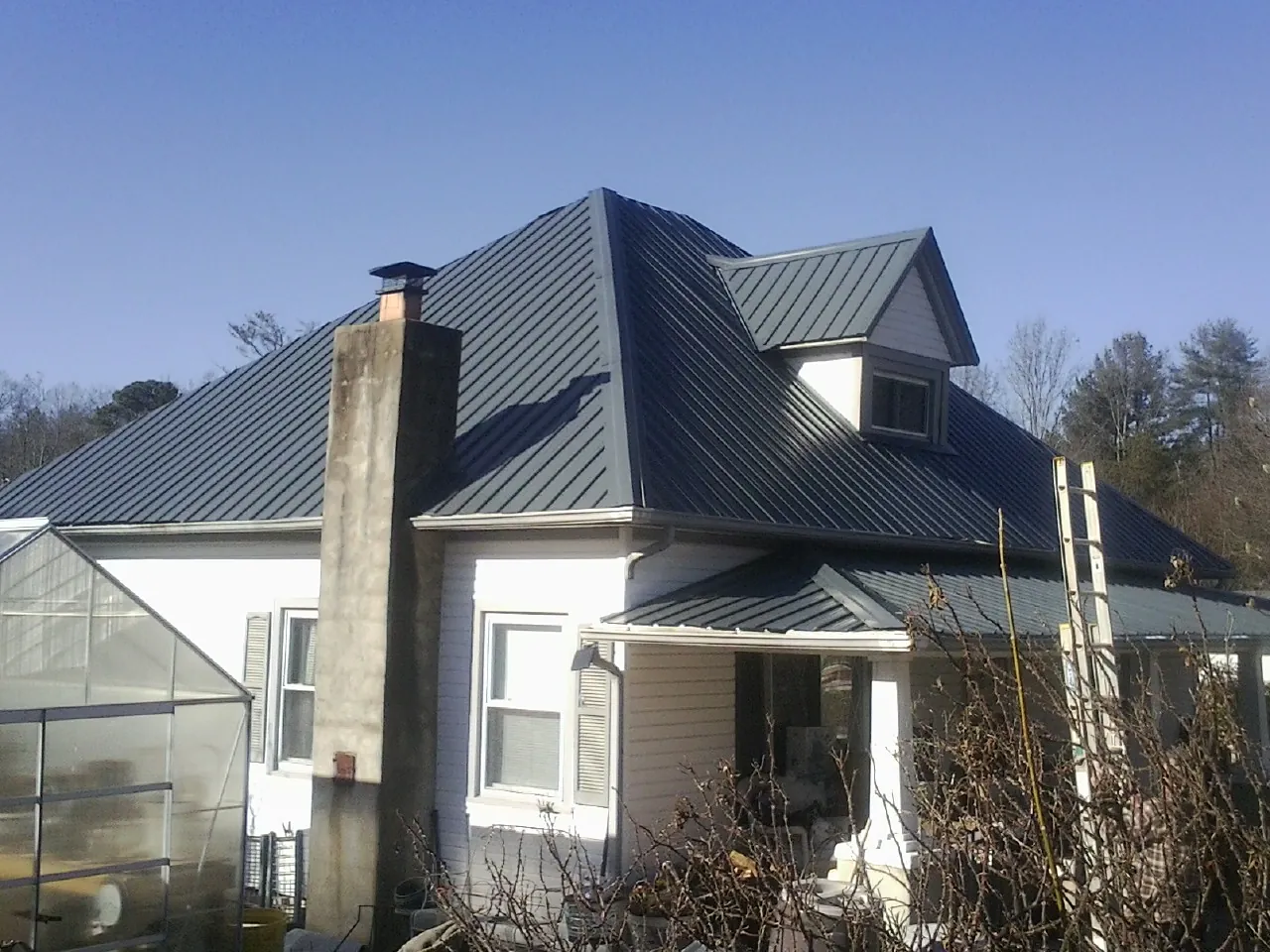 Dark blue standing seam metal roof on a white farmhouse with dormer — Slate & Tile Roof Repair by Roofing Brothers in Bordentown