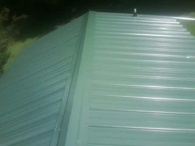 New green metal panels meeting at the ridge of a roof — Flat Roof Repair work by our crew in Bordentown
