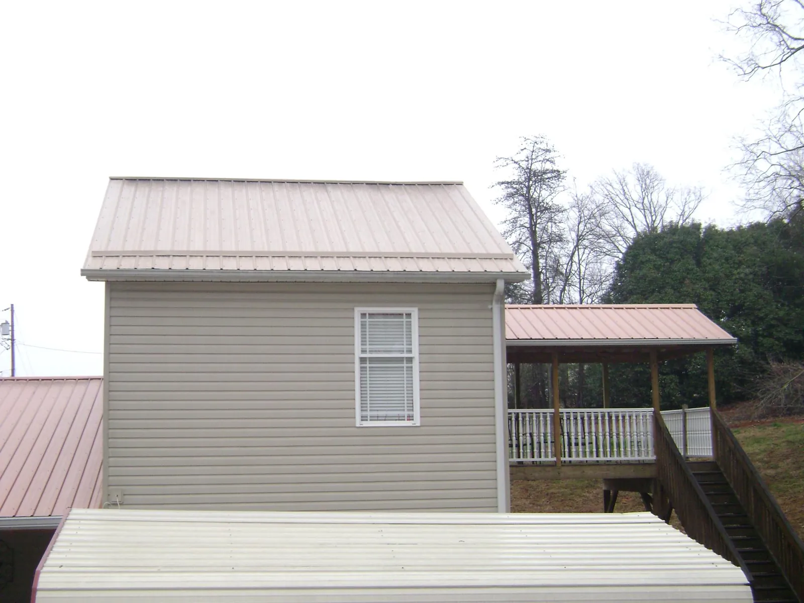 Tan metal roofs on a two story addition and attached porch, from a Roof Replacement job in Bordentown