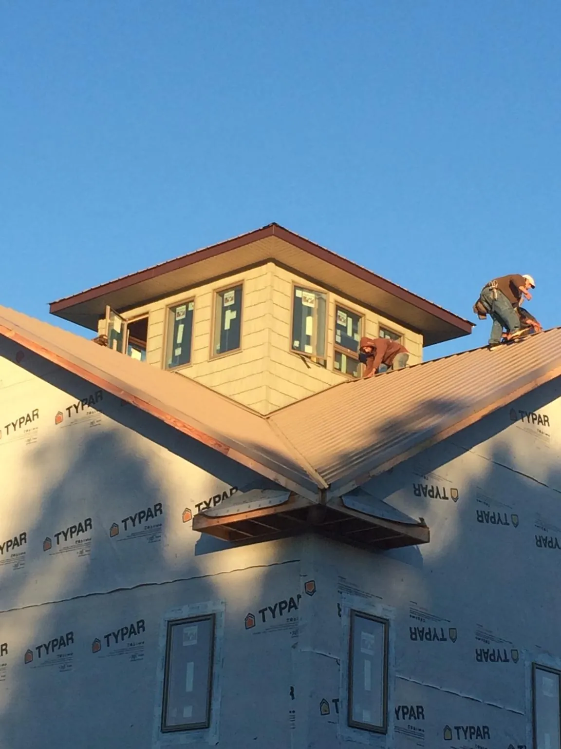 Roofers working around a rooftop cupola on a new metal roof at sunset — Roof Waterproofing in Bordentown by Roofing Brothers